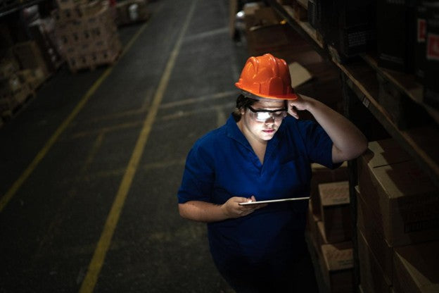 A factory employee works in the dark because of a generator failure due to missed maintenance. 