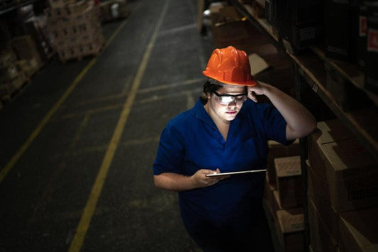 A factory employee works in the dark because of a generator failure due to missed maintenance. 