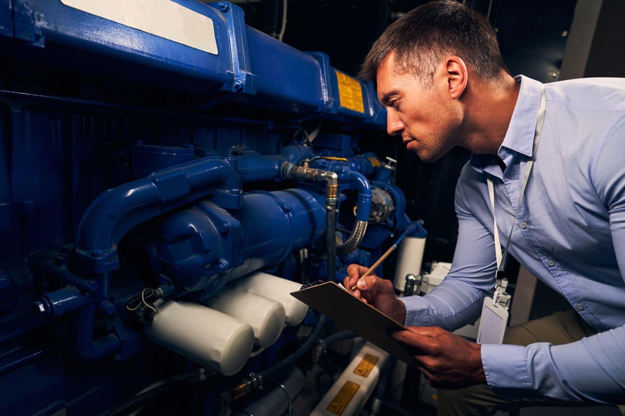Technician inspecting an industrial standby generator during commercial generator maintenance.