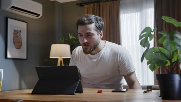 Man sitting at a desk using a tablet in a home office.